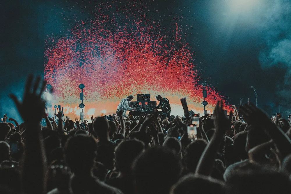 A concert crowd beneath a burst of red confetti