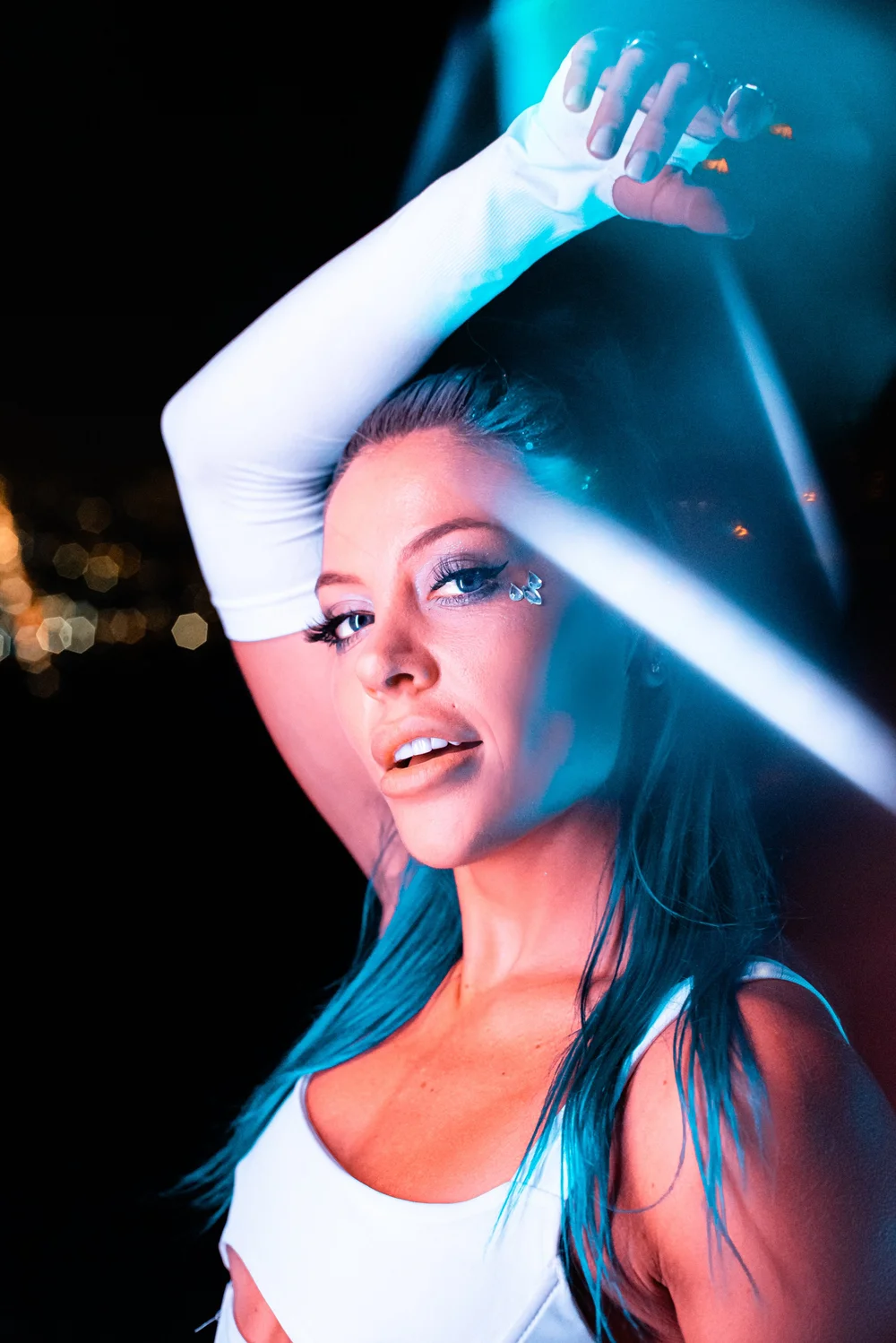 Portrait of a woman in blue stage light with one arm raised