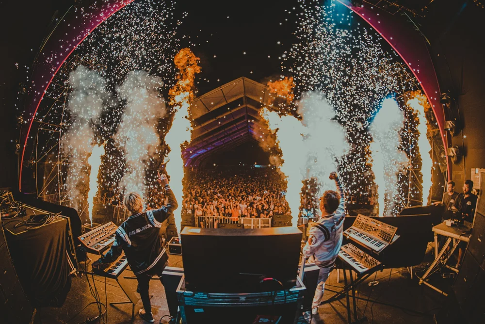 Performers framed by fountains of sparks on a concert stage